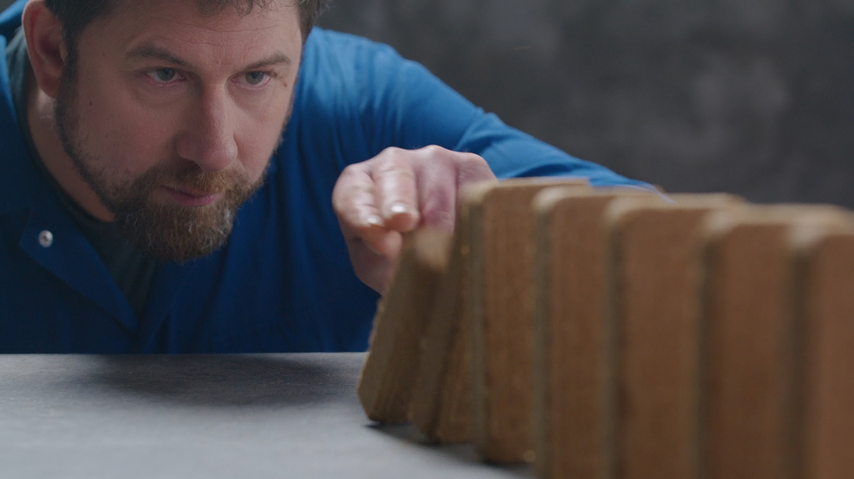 Man about to push over a Milkiwean ActiBar stacked as dominos